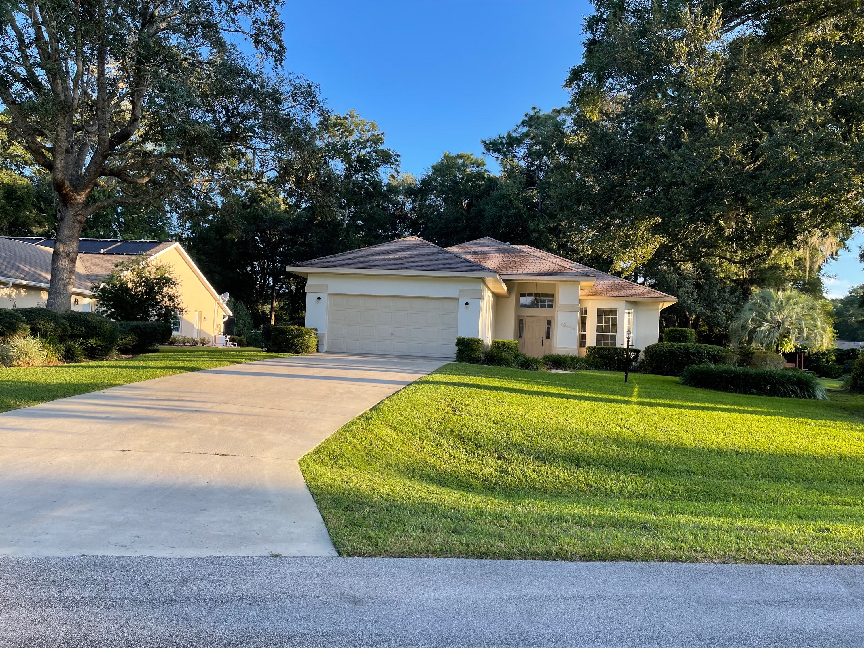 Residential home at golden hour with sweeping green lawn and curved driveway