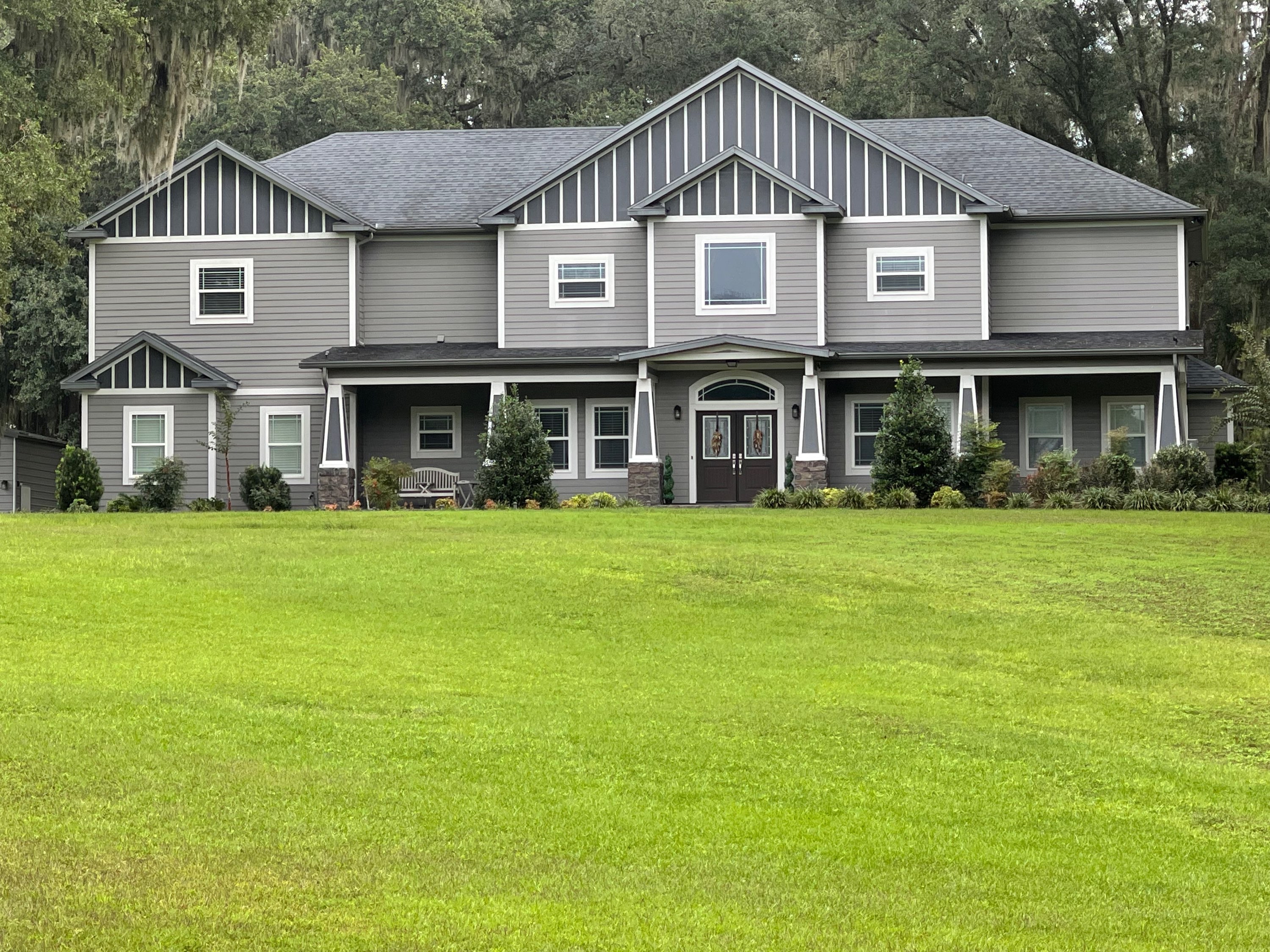 Large two-story craftsman home with wide, perfectly manicured bright green lawn