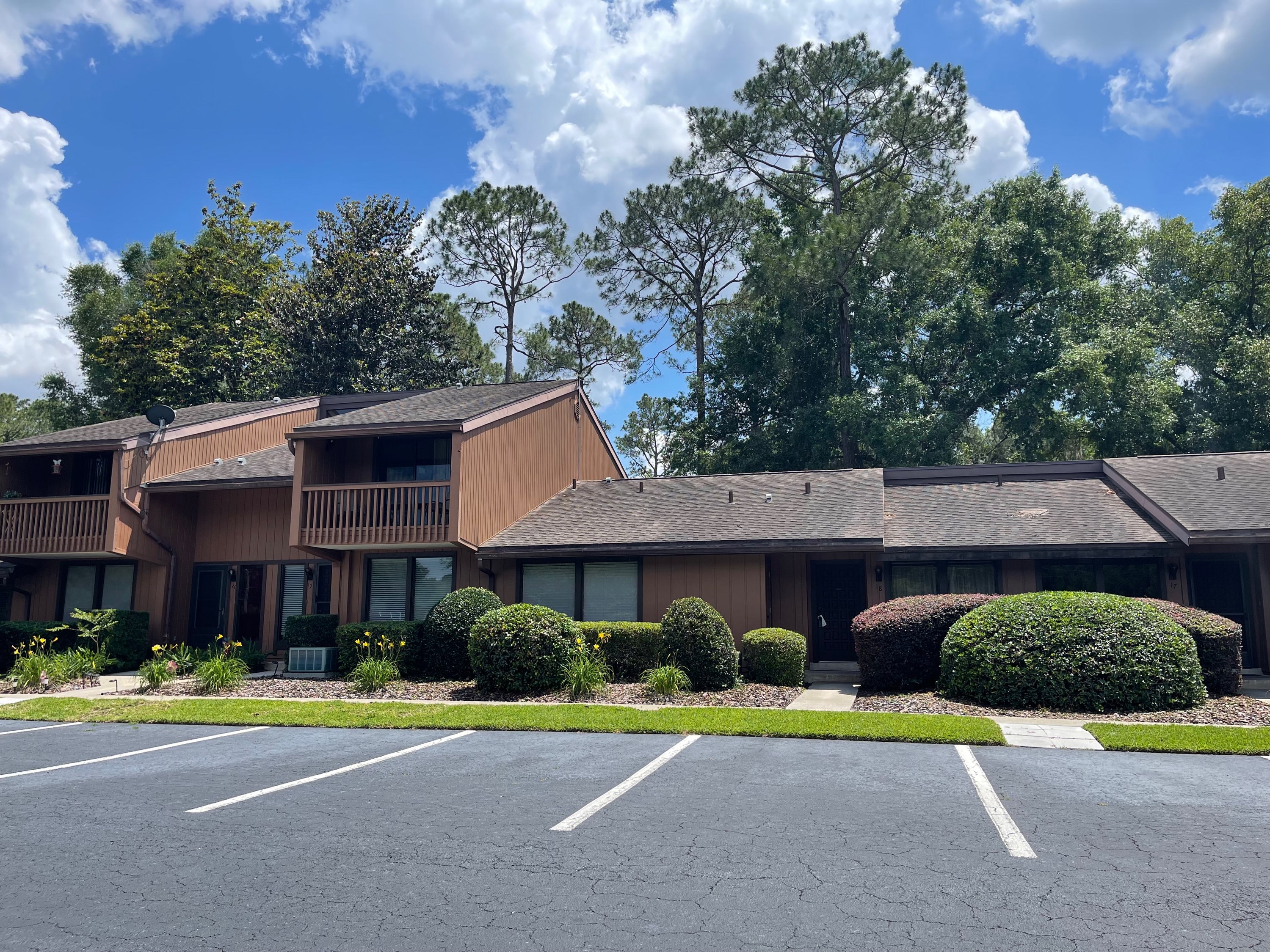 Well-maintained condo complex with neatly trimmed round shrubs and rock beds