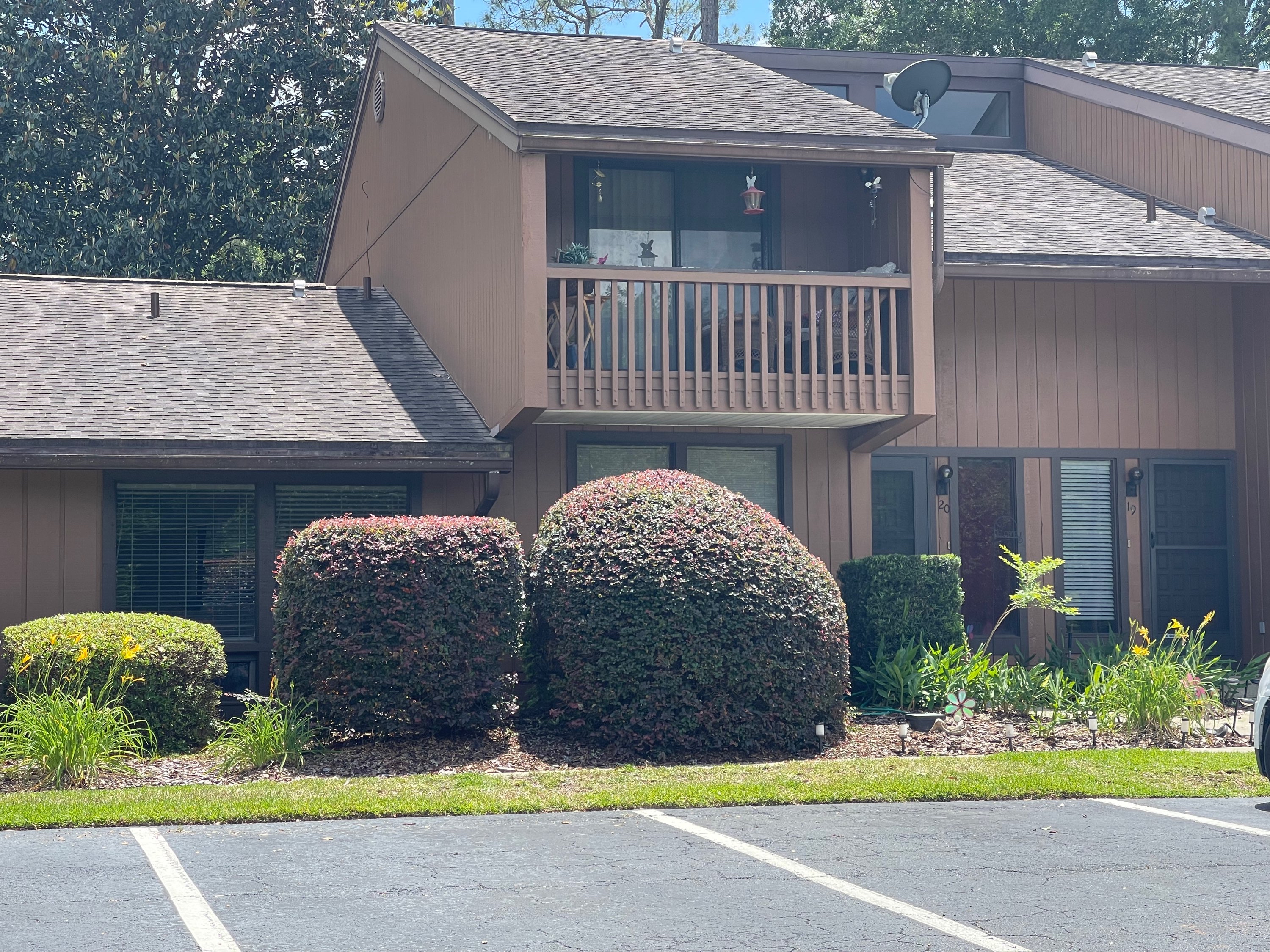 Condo front with neatly trimmed red-leaf and green shrubs in fresh mulch beds