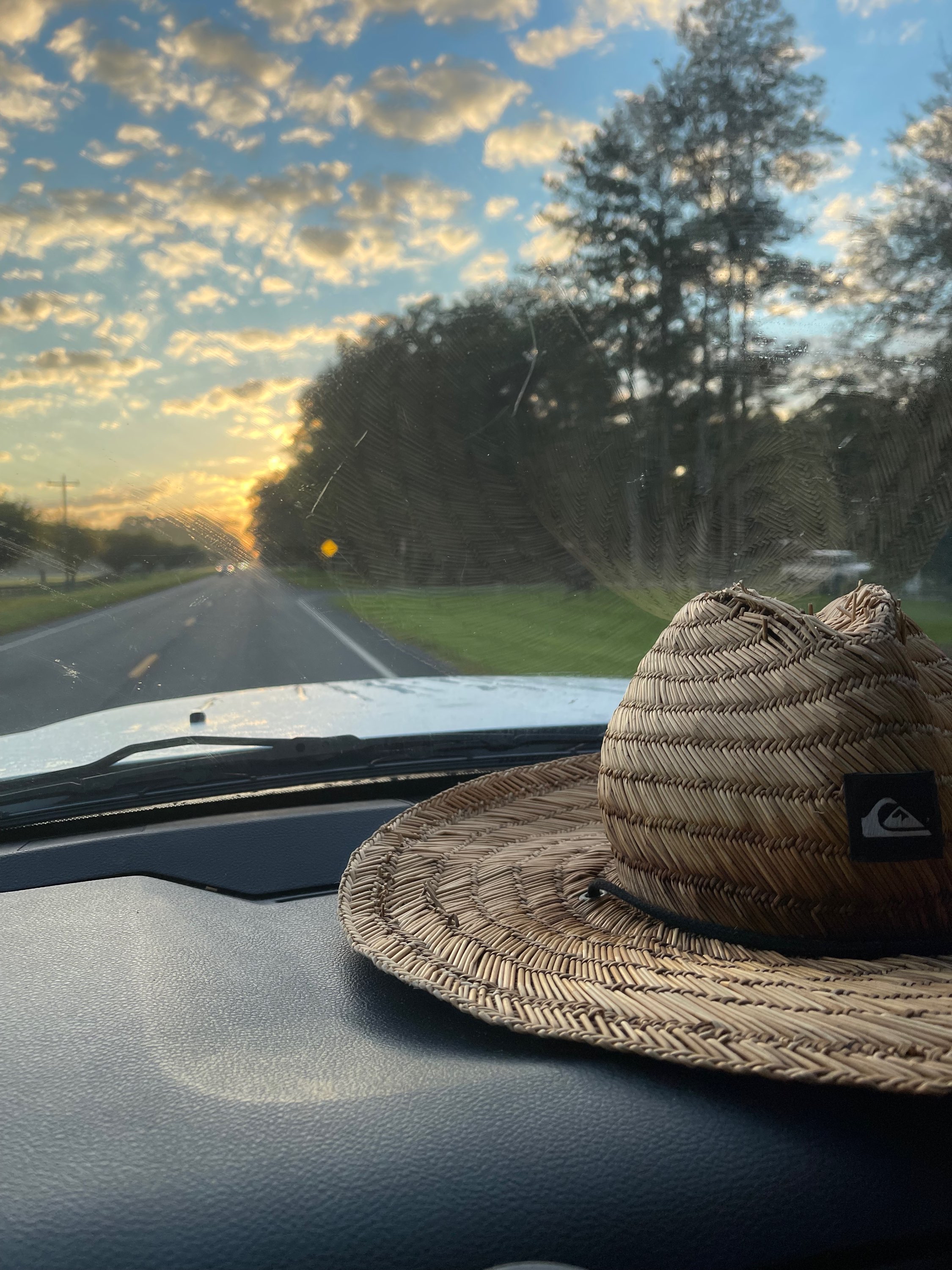 Straw hat on truck dashboard with beautiful sunrise through the windshield