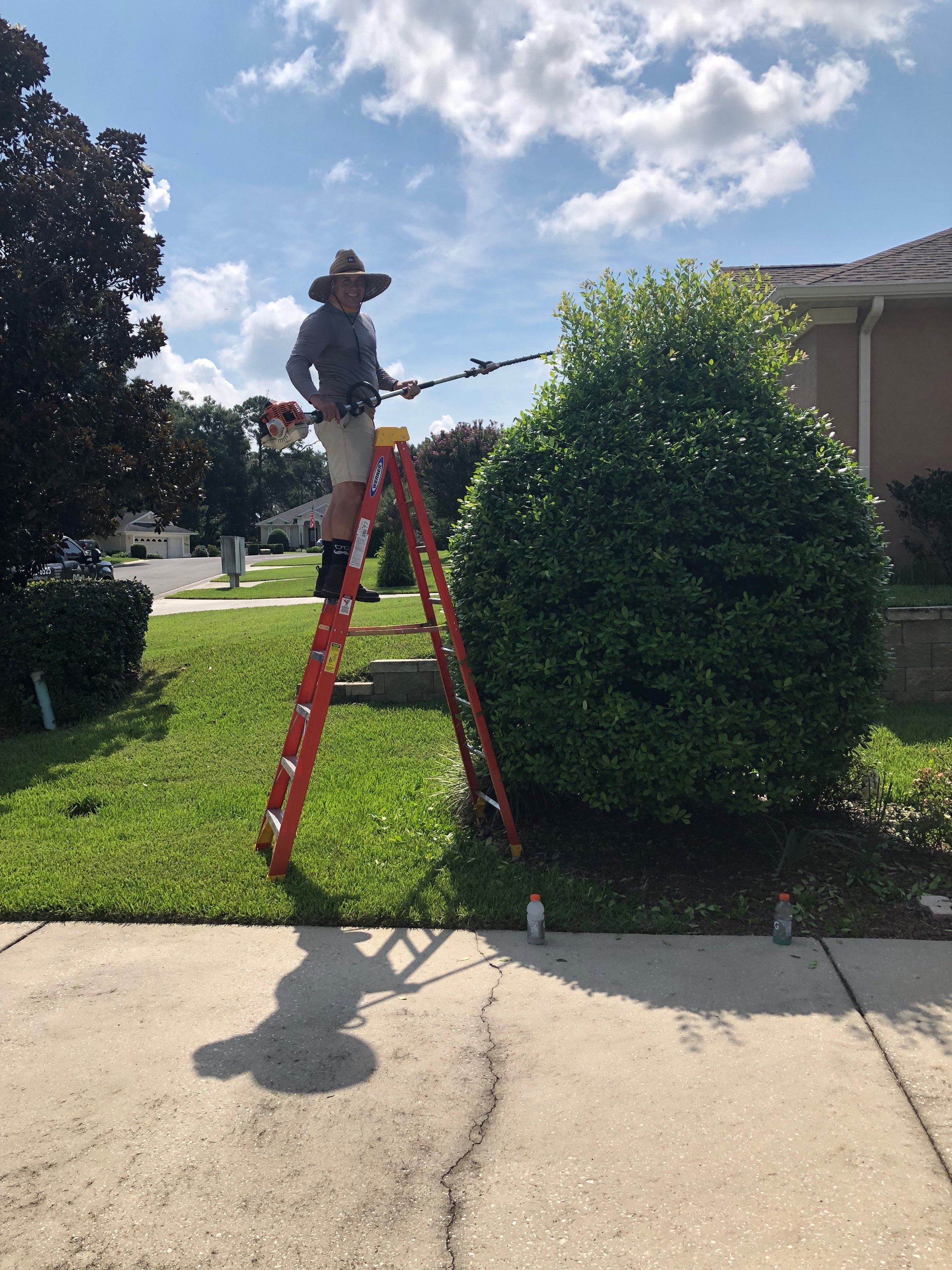 Crew member on orange ladder working at roofline height